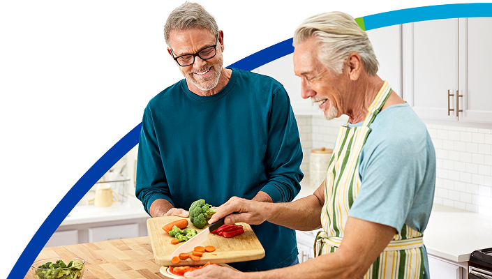 Two senior males cooking a healthy meal in the kitchen.